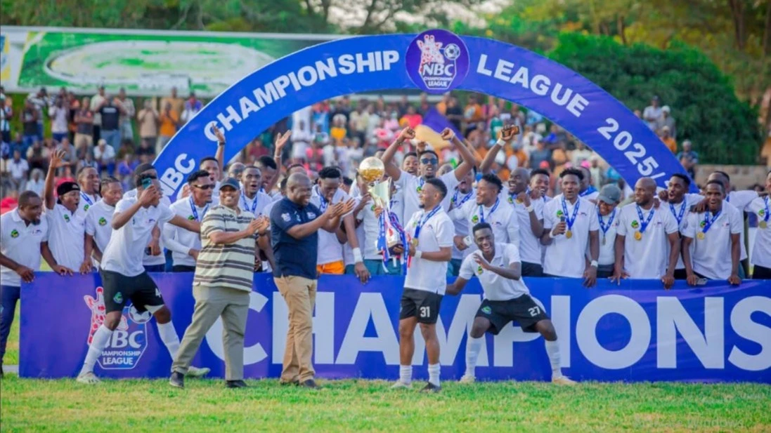 NBC Lake Zone Business Head Mafwimbo Bihemo ((in a black T-shirt),) and Tanzania Football Federation (TFF) President Wallace Karia (wearing a cap) congratulate Geita Gold FC players after the club was crowned 2025/26 NBC Championship champions.