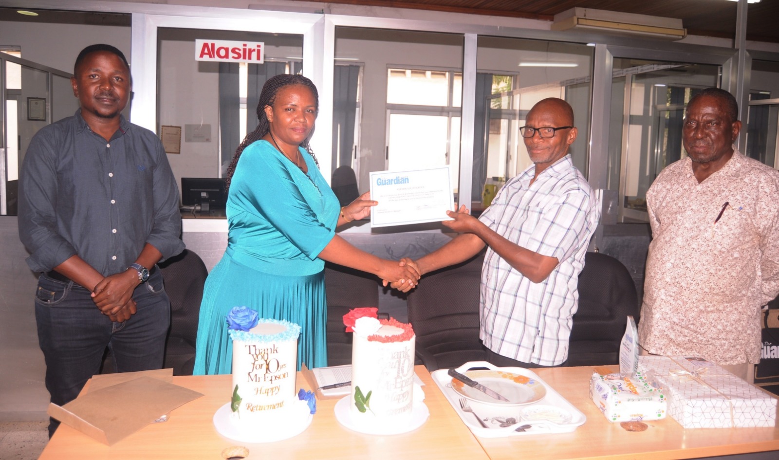 Haika Lekey (2nd-L), Human Resources Manager with The Guardian Ltd (publishers of The Guardian and Nipashe newspapers), presents a certificate of service to the Editor of the weekend issues of Nipashe newspaper, Epson Luhwago, at the TGL newsroom in DSM.